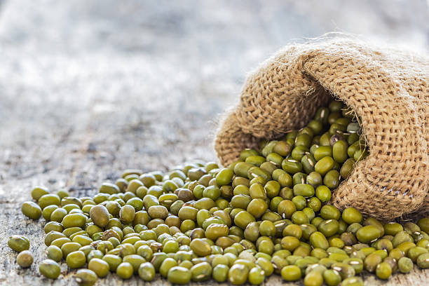 Close up shot Mung beans poured from the sack on old wood table